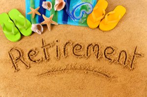 The word Retirement written on a sandy beach, with scuba mask, beach towel, starfish and flip flops (studio shot - warm color and directional light are intentional).